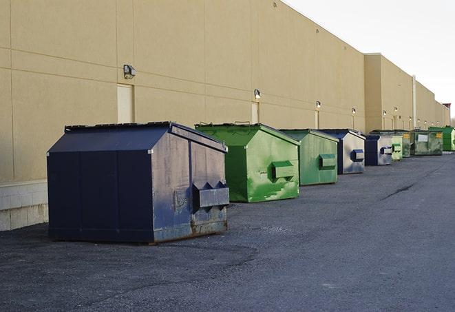 tilted front-load dumpsters being emptied by waste management workers in Bardonia